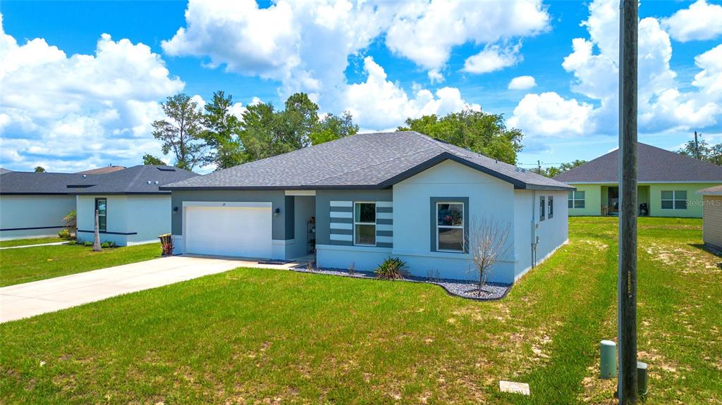 A single-story house with a white garage, grey accents, and a grey shingled roof — 217 BEGONIA LANE, POINCIANA, FL