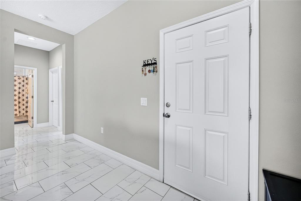 An entryway features white tile flooring, a white front door, and a wall-mounted key rack — 217 BEGONIA LANE, POINCIANA, FL