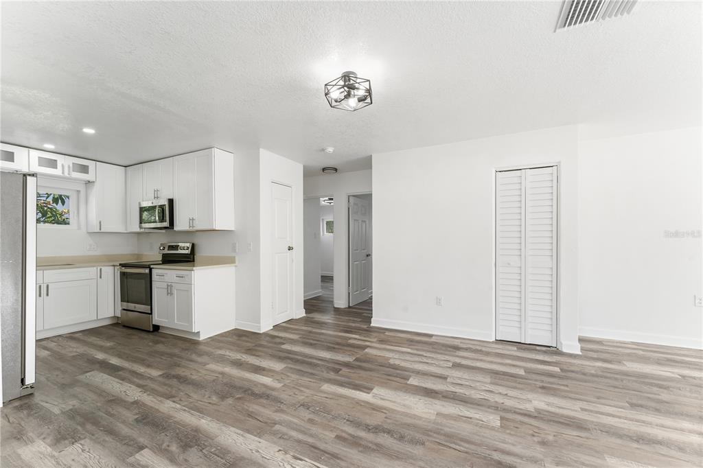 A kitchen with white cabinets and stainless steel appliances opens to a living area — 6221 FLORIDA CIRCLE E, APOLLO BEACH, FL