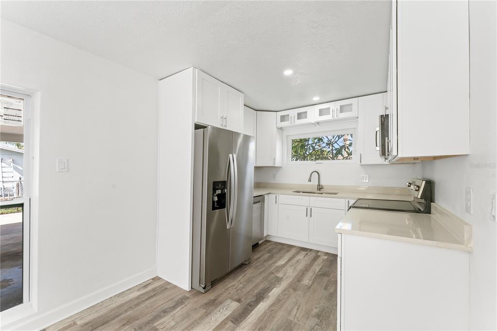 A kitchen with white cabinets, stainless steel appliances, and light wood-look flooring — 6221 FLORIDA CIRCLE E, APOLLO BEACH, FL