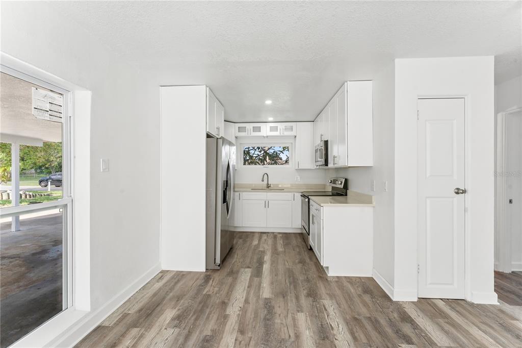 A kitchen with white cabinets, stainless steel appliances, and wood-look flooring — 6221 FLORIDA CIRCLE E, APOLLO BEACH, FL