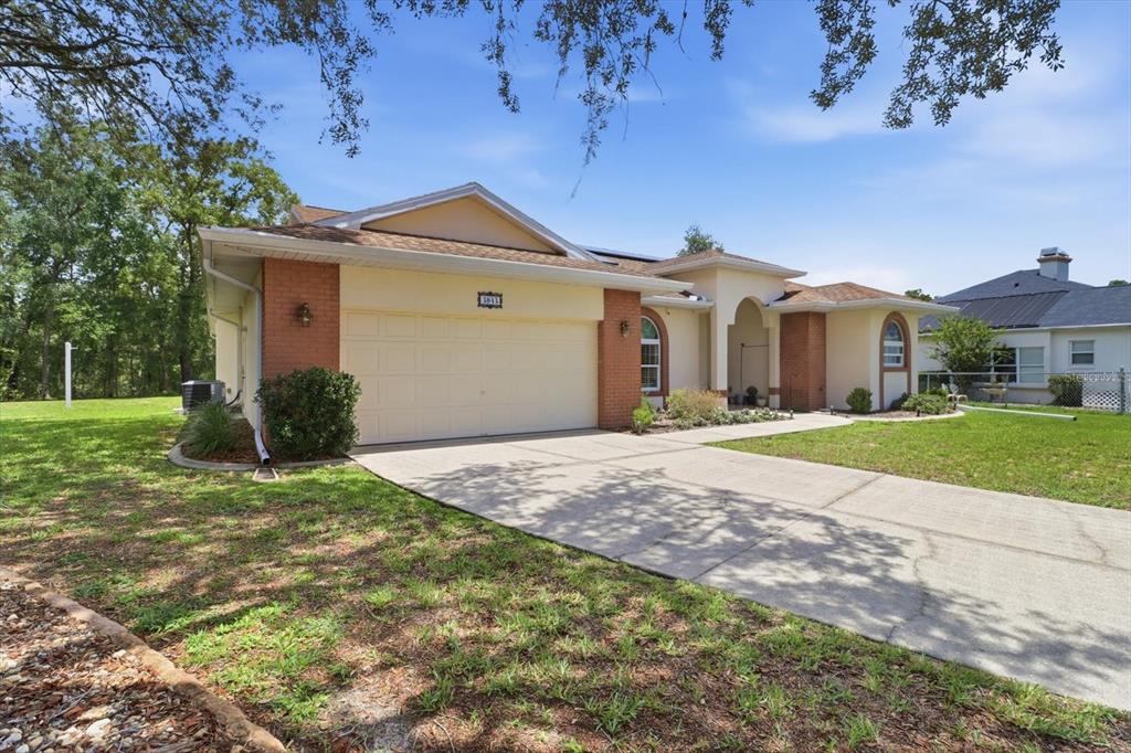 A single-story house with a two-car garage, brick accents, and a concrete driveway — 3843 W NORTHCREST COURT, LECANTO, FL