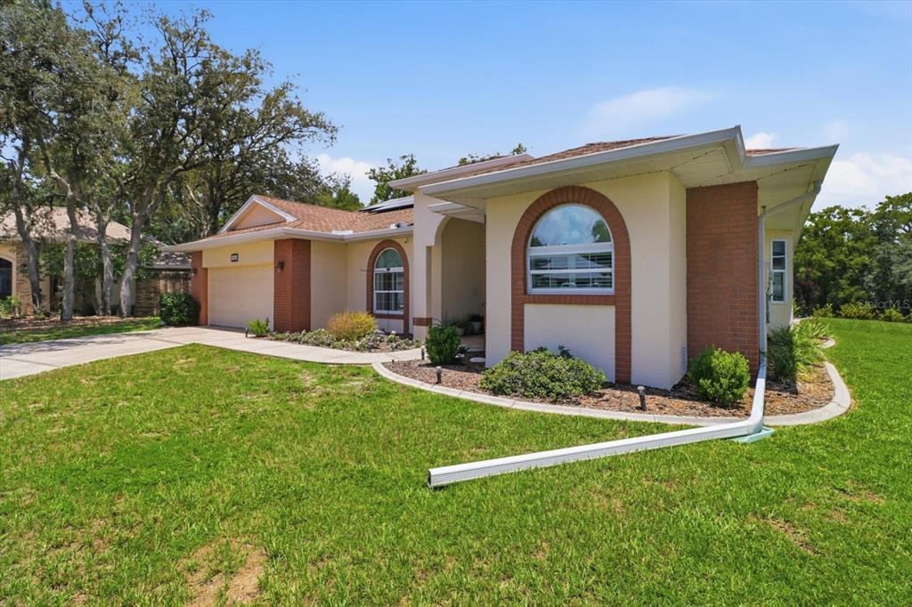A single-story house with a tan stucco exterior, brick accents, and a two-car garage — 3843 W NORTHCREST COURT, LECANTO, FL