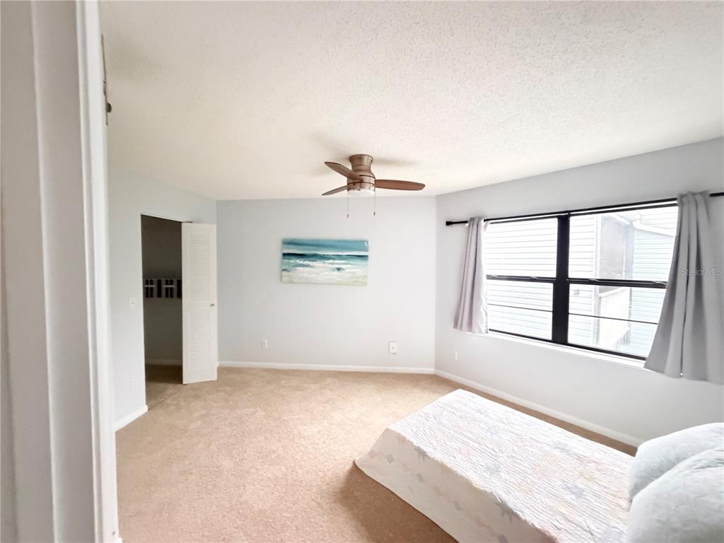 A bedroom features beige carpeting, light blue walls, a ceiling fan, and a window with curtains — 3914 ATRIUM DRIVE UNIT U1, ORLANDO, FL