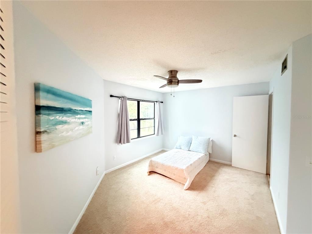 A bedroom features beige carpeting, a ceiling fan, a window with curtains, and a bed — 3914 ATRIUM DRIVE UNIT U1, ORLANDO, FL