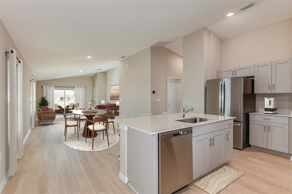 A kitchen with a center island and stainless steel appliances opens to a dining area — 36618 SAGEMOOR DRIVE, ZEPHYRHILLS, FL