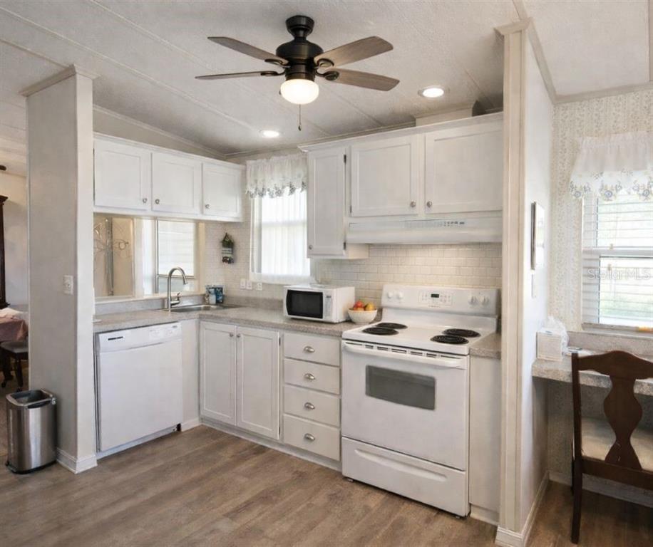 A kitchen with white cabinets, white appliances, a ceiling fan, and light wood-look flooring — 145 JANA CIRCLE, AUBURNDALE, FL