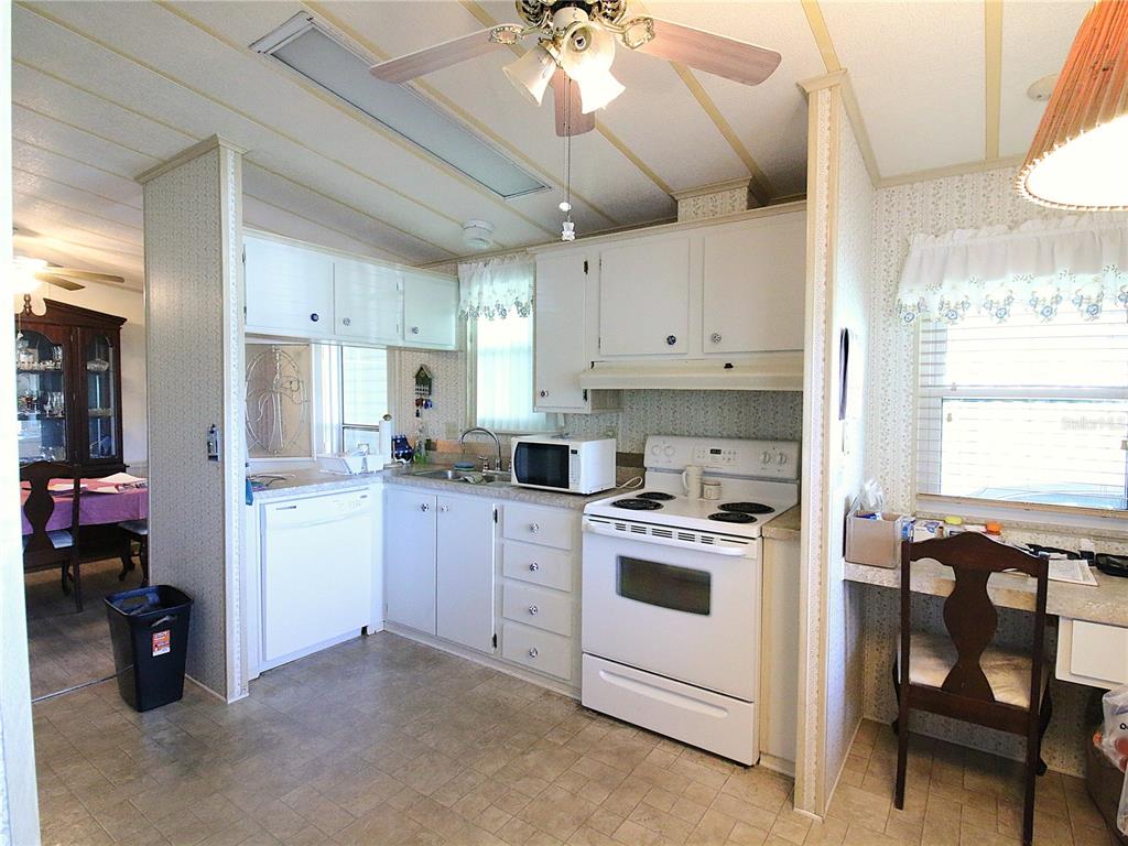 A kitchen with white cabinets, white appliances, and a small built-in desk area — 145 JANA CIRCLE, AUBURNDALE, FL