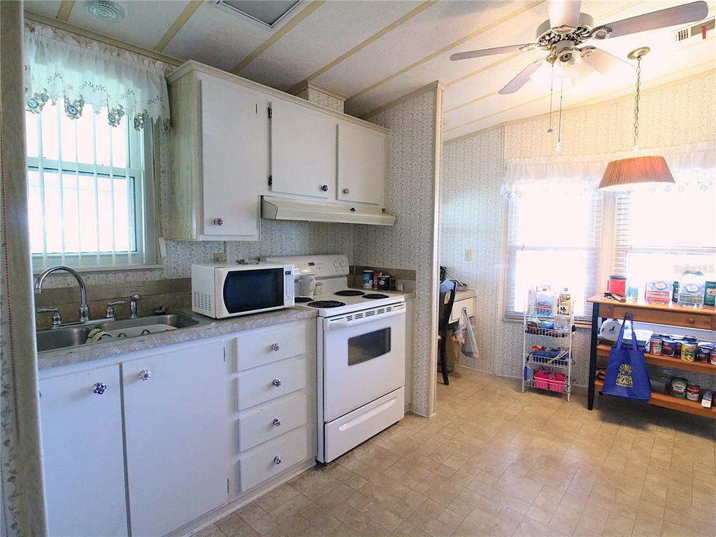 A kitchen with white cabinets, white appliances, a microwave, and a ceiling fan — 145 JANA CIRCLE, AUBURNDALE, FL
