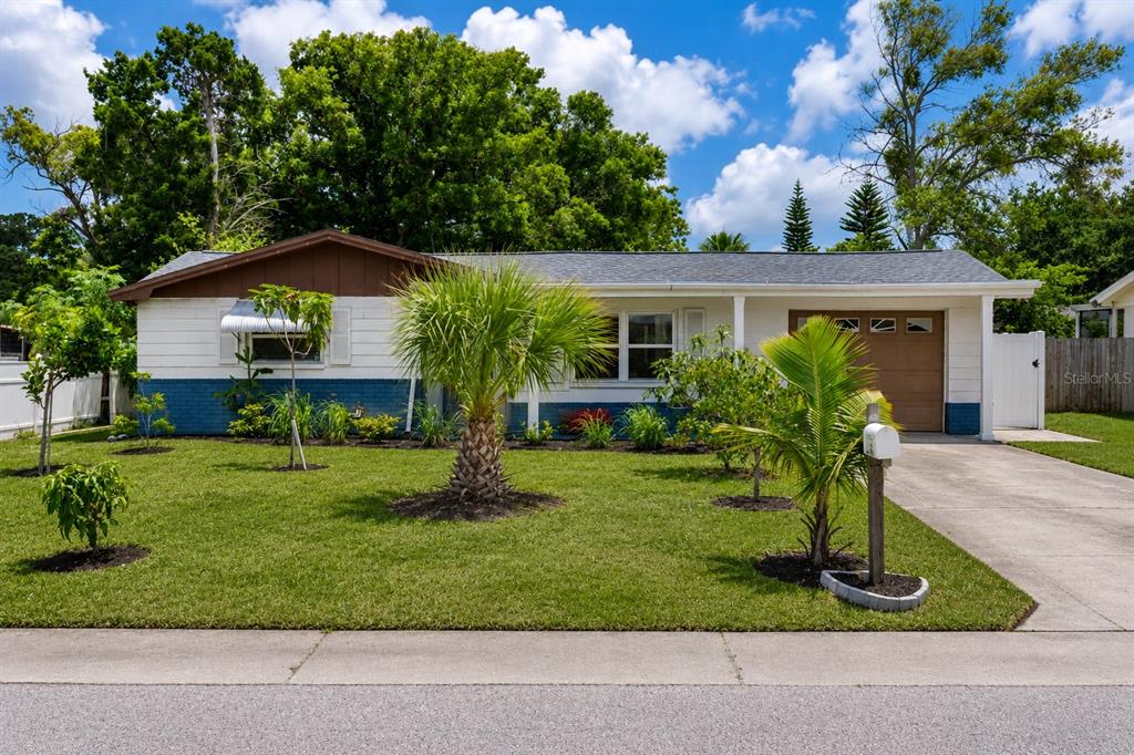 A single-story house with white and blue siding, a brown garage door, and a front lawn — 3302 ROCK ROYAL DRIVE, HOLIDAY, FL