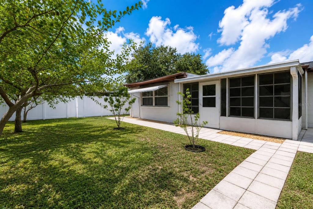 A backyard with a white fence, a paved walkway, and a screened-in porch on a house — 3302 ROCK ROYAL DRIVE, HOLIDAY, FL