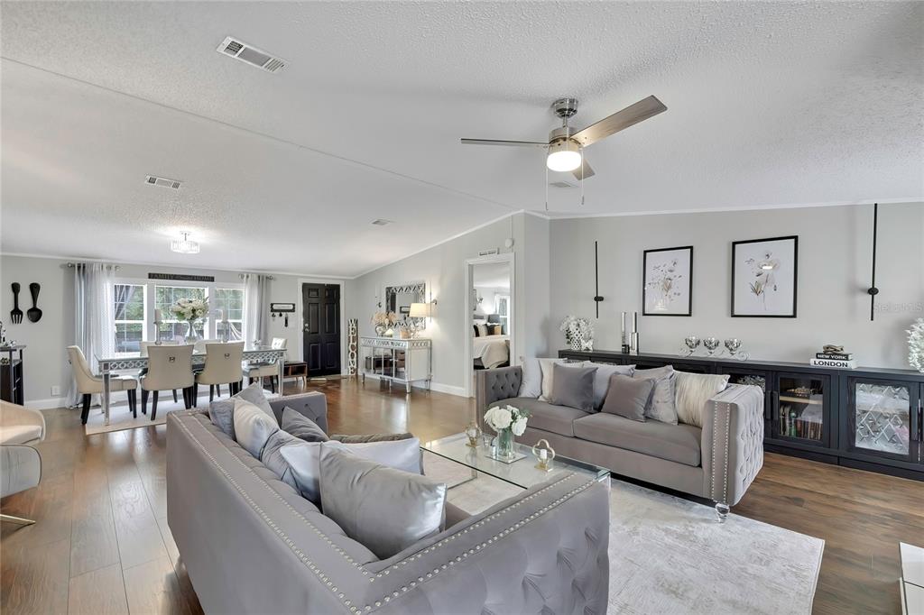 A spacious living room features grey tufted sofas, a dining area, and hardwood flooring — 6171 S LISA POINT, HOMOSASSA, FL