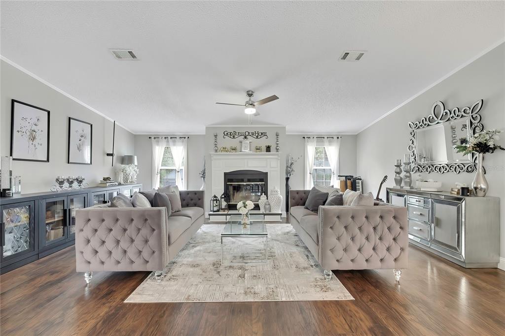A living room features two tufted grey sofas, a central fireplace, and dark wood flooring — 6171 S LISA POINT, HOMOSASSA, FL