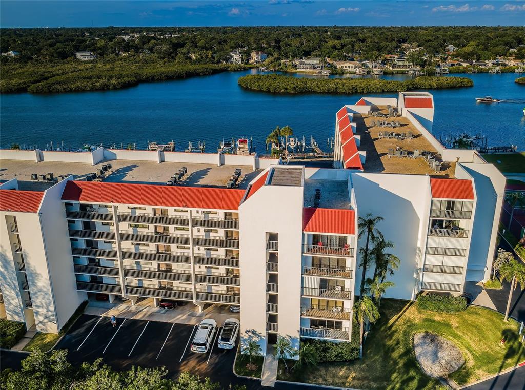 An aerial view of a multi-story apartment building with red roofs next to a waterway — 19111 VISTA BAY DRIVE UNIT 304, INDIAN SHORES, FL