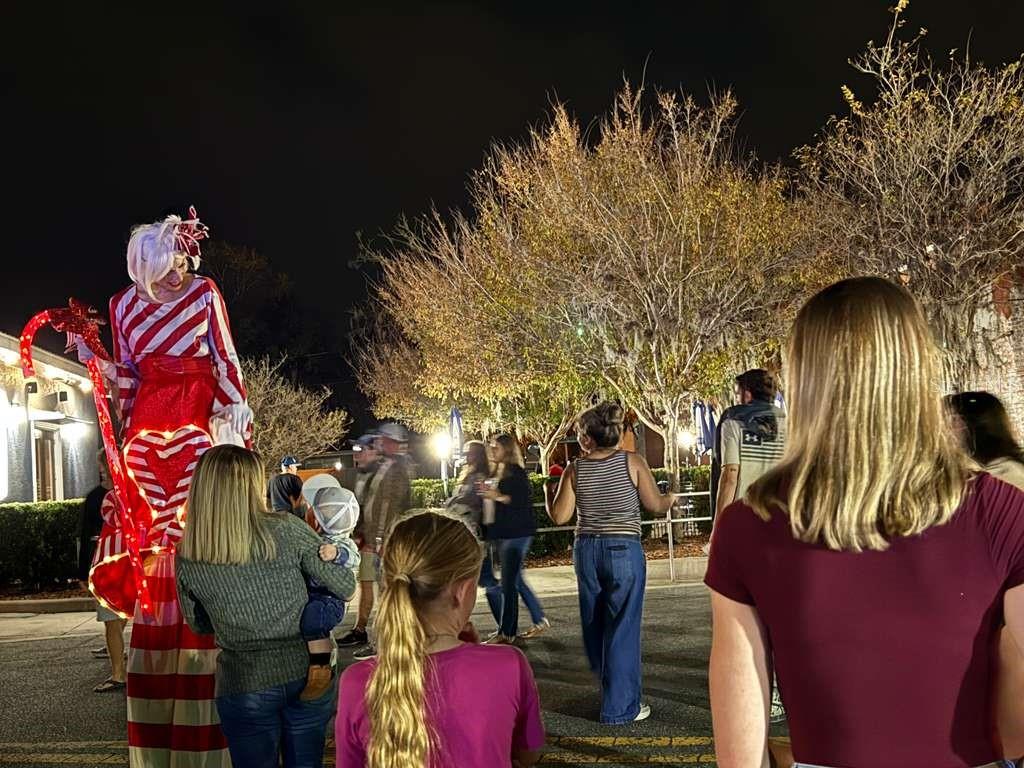 A stilt walker in a candy cane costume interacts with a crowd at night — 5636 W JUNIOR LANE, DUNNELLON, FL