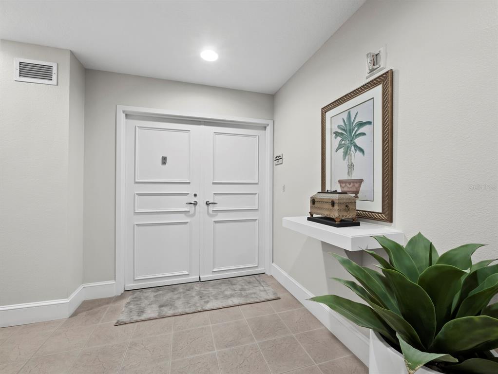 A white double door entry features a floating shelf, framed artwork, and a potted plant — 3080 GRAND BAY BOULEVARD UNIT 512, LONGBOAT KEY, FL