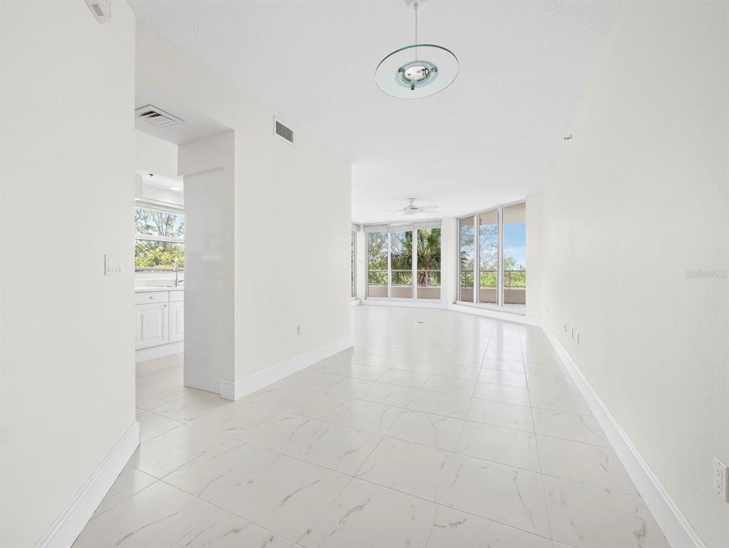 A dining area with a round table and chairs opens into a living room with balcony — 3080 GRAND BAY BOULEVARD UNIT 512, LONGBOAT KEY, FL
