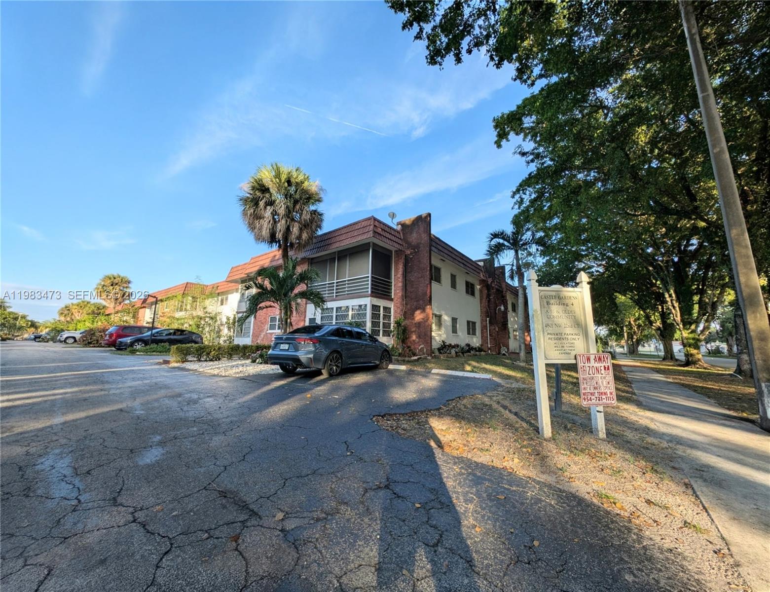 An exterior view of a multi-story apartment building with a parking lot and signage — 4801 NW 22nd Ct # 205, Lauderhill FL 33313, LAUDERHILL, FL