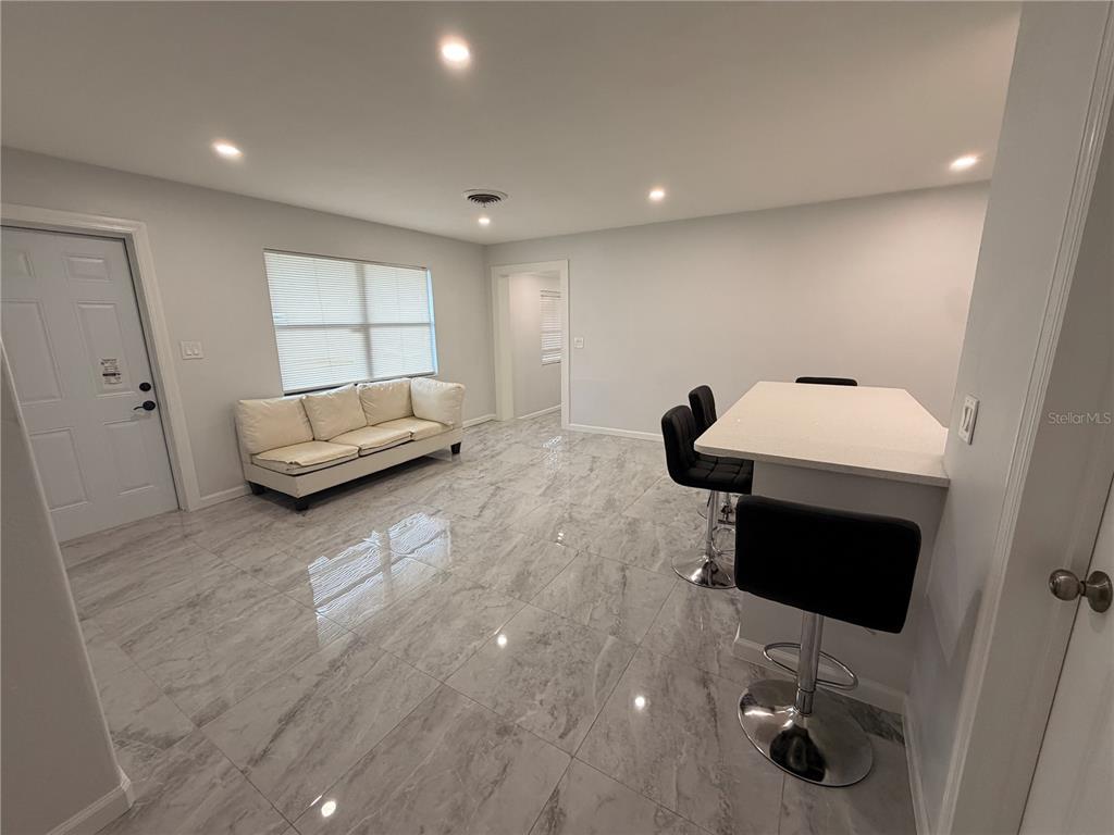 A room with gray marble-look tile flooring, a white sofa, and a breakfast bar — 1144 36TH STREET W, BRADENTON, FL