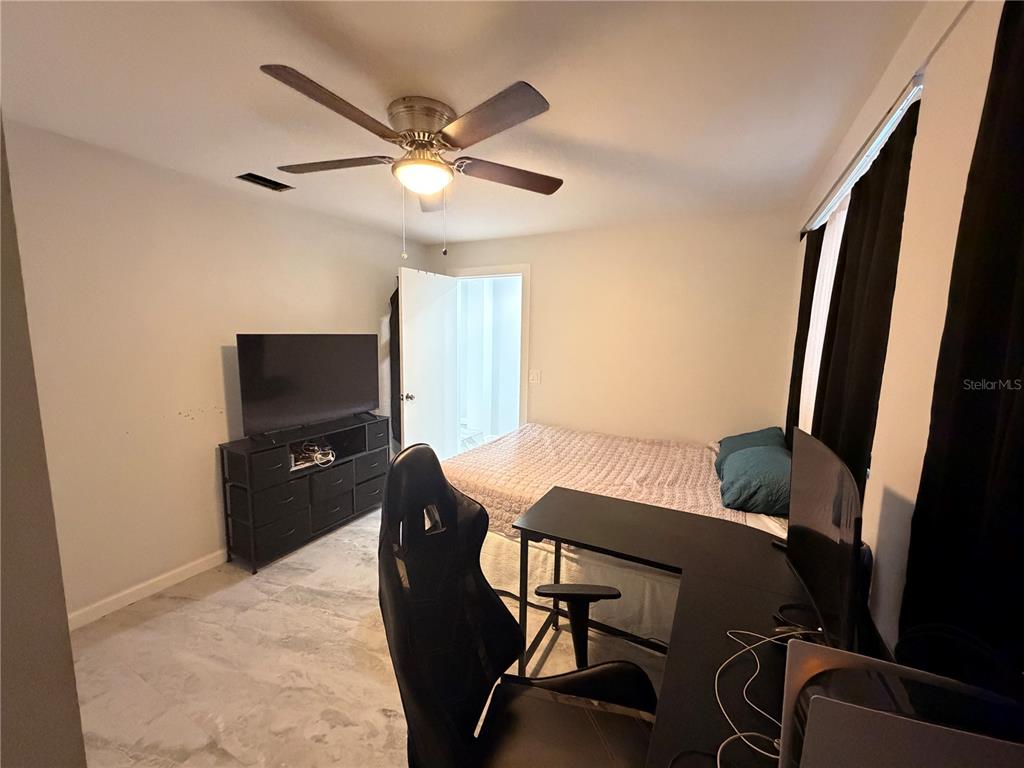 A bedroom features a bed, a desk with a gaming chair, and a television stand — 1144 36TH STREET W, BRADENTON, FL