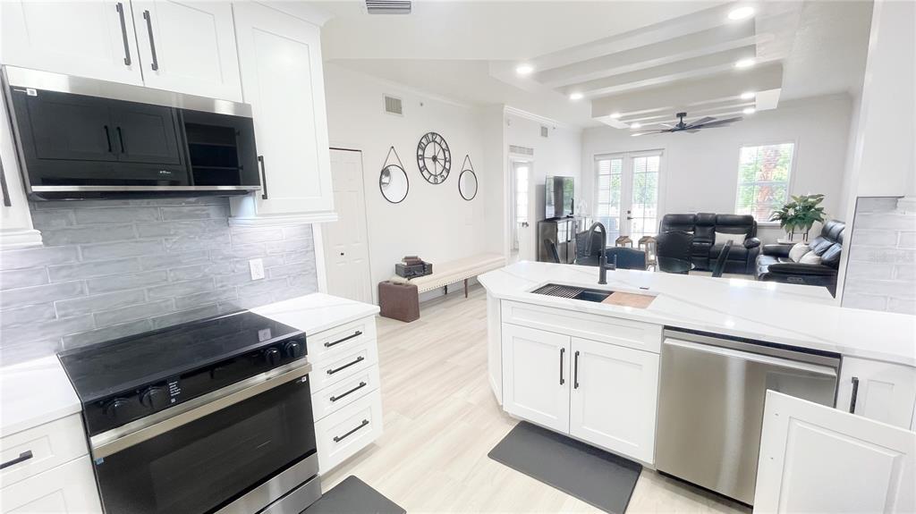 A modern kitchen with white cabinets, stainless steel appliances, and a central island — 1501 NORTHERN HARRIER WAY UNIT 202, REUNION, FL