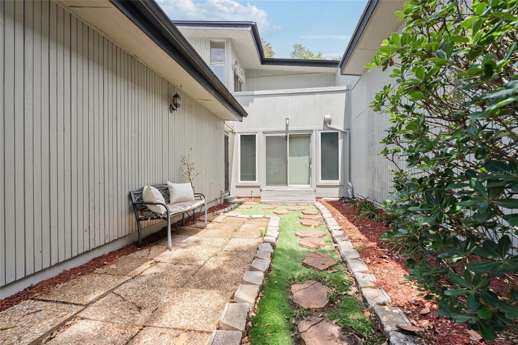 A narrow outdoor courtyard features a stone patio, a bench, and a stepping stone path — 1923 LAKE ALDEN DRIVE UNIT A, APOPKA, FL