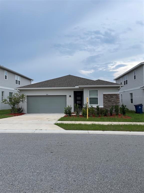 A single-story house with a gray garage, stone accents, and a dark front door — 1055 SUGARWOOD STREET, DAVENPORT, FL