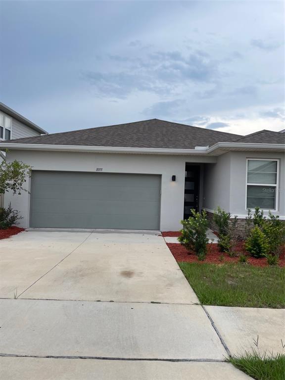 A single-story house with a gray garage door, a front entrance, and a concrete driveway — 1055 SUGARWOOD STREET, DAVENPORT, FL