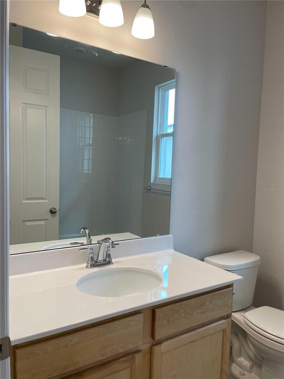 A bathroom features a wooden vanity with a white countertop, a mirror, and a toilet — 1055 SUGARWOOD STREET, DAVENPORT, FL