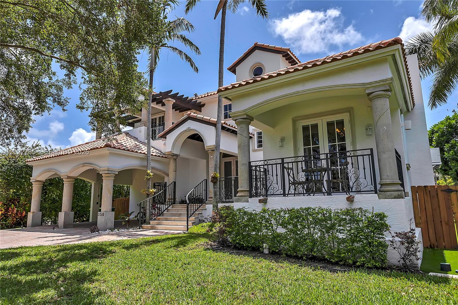 A two-story Mediterranean-style house features a tiled roof, arched entryway, and a front porch — 350 Redwood Ln, Key Biscayne FL 33149, KEY BISCAYNE, FL