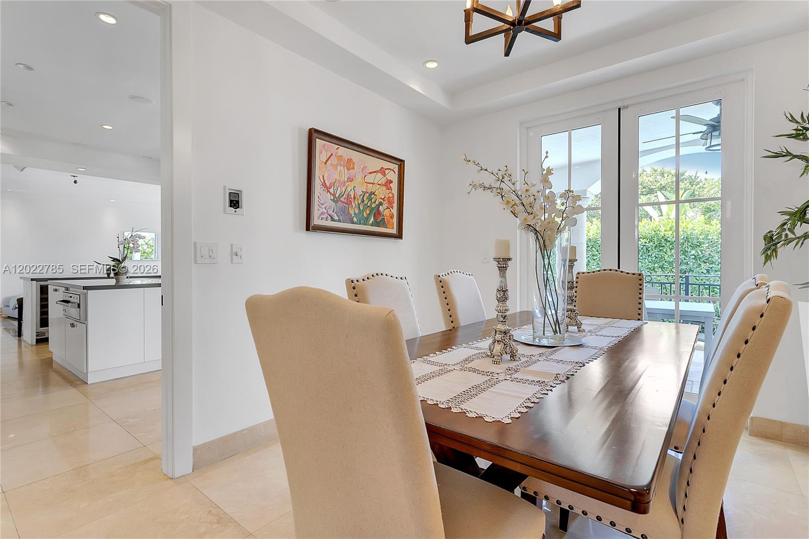 A dining room features a wooden table, upholstered chairs, and a view of a patio — 350 Redwood Ln, Key Biscayne FL 33149, KEY BISCAYNE, FL