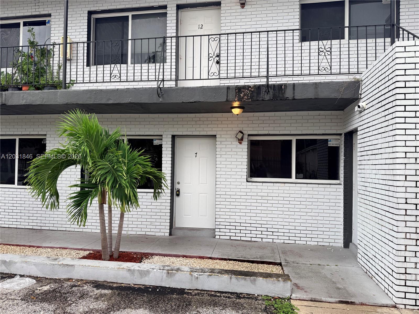 A two-story white brick apartment building features a palm tree and numbered entry doors — 7824 NW 5th Ct # 7, Miami FL 33150, MIAMI, FL
