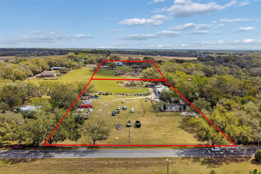 An aerial view shows a large, fenced residential lot with multiple structures and scattered debris — 8236 WIRE ROAD, ZEPHYRHILLS, FL
