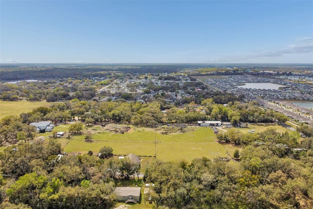 An aerial view shows a large, grassy lot surrounded by trees and residential neighborhoods — 8236 WIRE ROAD, ZEPHYRHILLS, FL