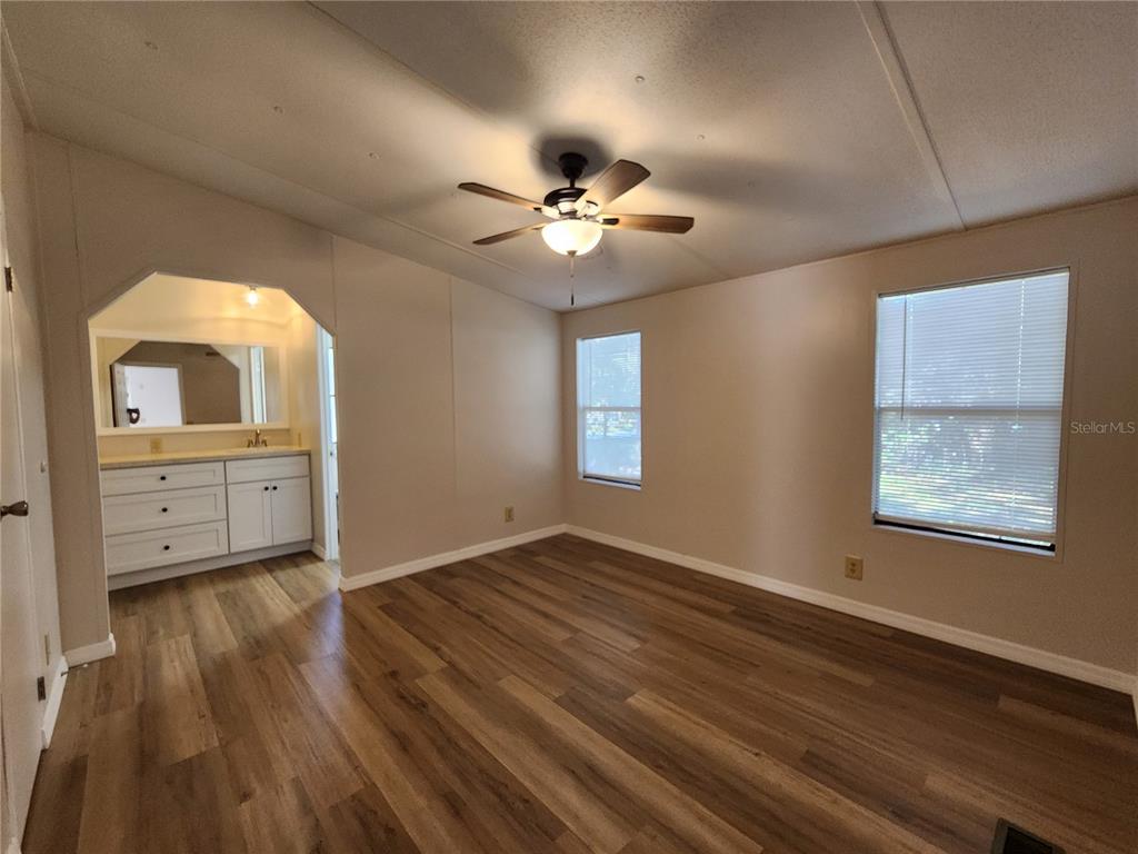 A bedroom with wood-look flooring, a ceiling fan, and an attached vanity area — 7351 NW 170TH STREET, TRENTON, FL