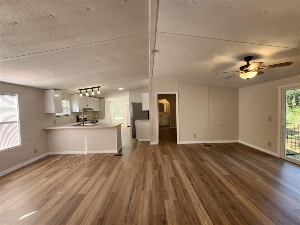 An open-concept living area features wood-look flooring, a kitchen with white cabinets, and a ceiling fan — 7351 NW 170TH STREET, TRENTON, FL