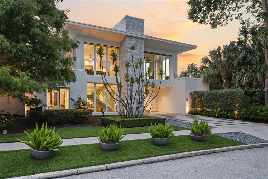 A modern two-story house features a stone chimney, large glass windows, and a landscaped yard — 229 ALEXANDER PLACE, WINTER PARK, FL