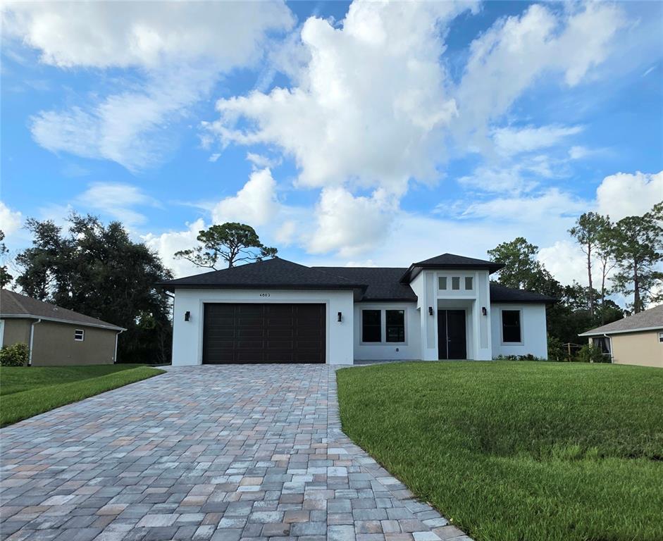 A single-story house with a dark garage door, white stucco exterior, and a paver driveway — 4802 SUNBURST AVENUE, NORTH PORT, FL