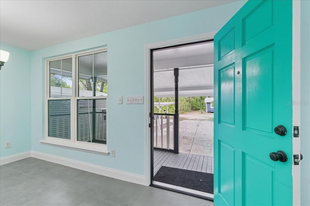 An interior view shows a light blue room with gray tile flooring and a turquoise door — 21445 SE 64TH AVENUE, HAWTHORNE, FL