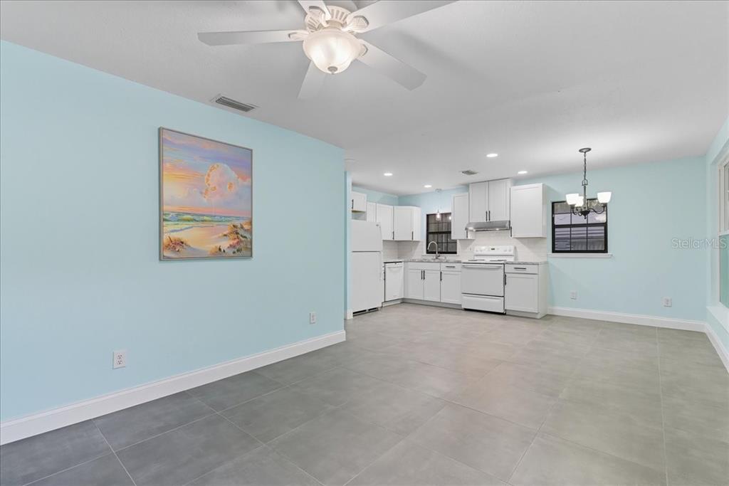 A kitchen and dining area with light blue walls, white cabinets, and gray tile flooring — 21445 SE 64TH AVENUE, HAWTHORNE, FL
