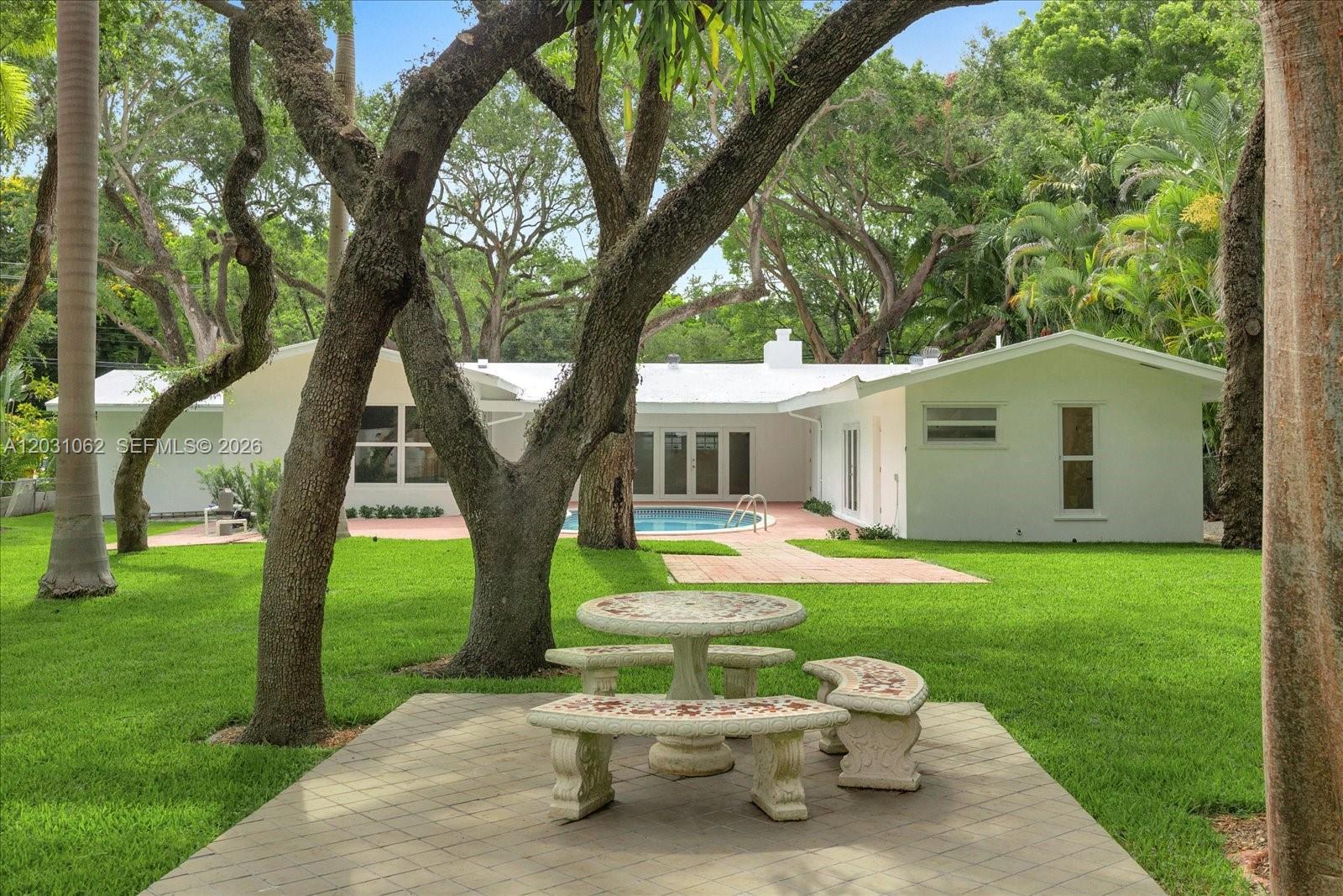 A backyard features a stone patio set, a swimming pool, and a white house — 2850 Natoma St # 0, Miami FL 33133, MIAMI, FL