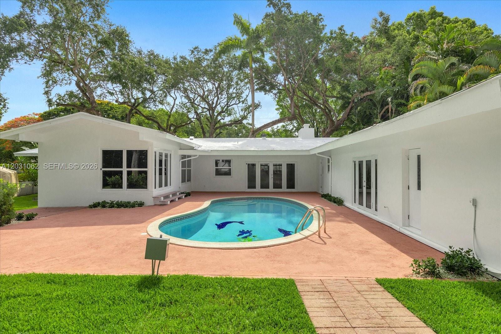 A white house with a kidney-shaped pool sits on a red patio under large trees — 2850 Natoma St # 0, Miami FL 33133, MIAMI, FL