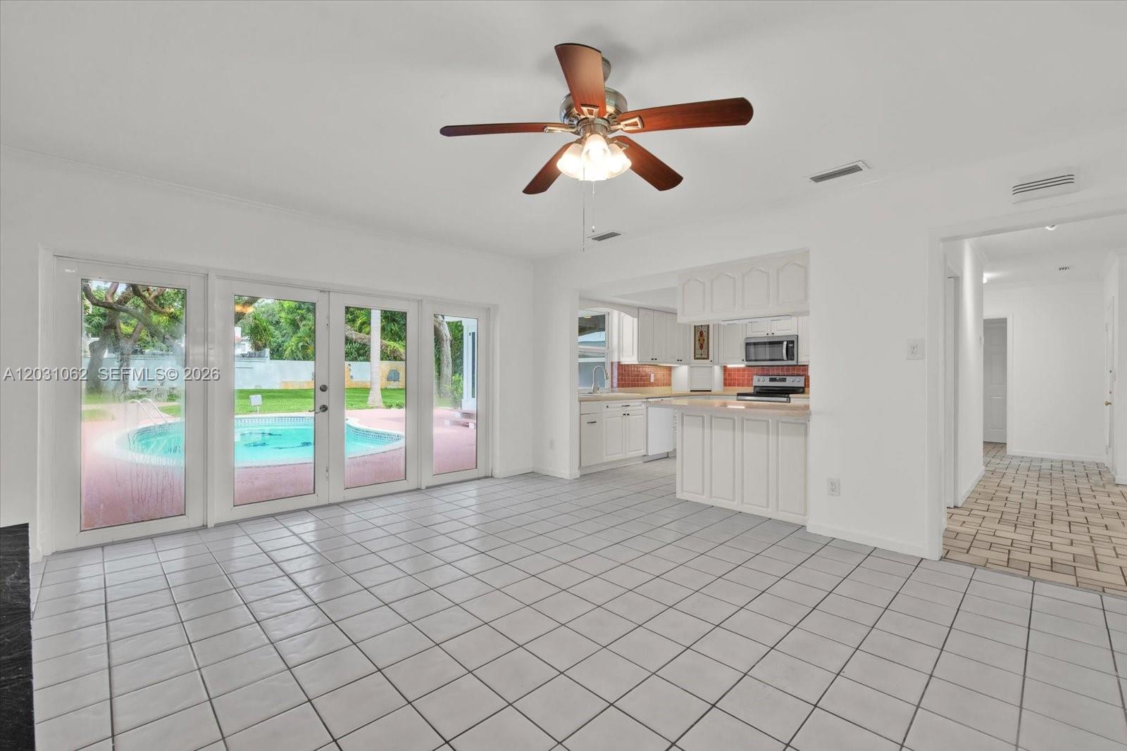 A tiled dining area features a ceiling fan, glass doors to a pool, and kitchen access — 2850 Natoma St # 0, Miami FL 33133, MIAMI, FL