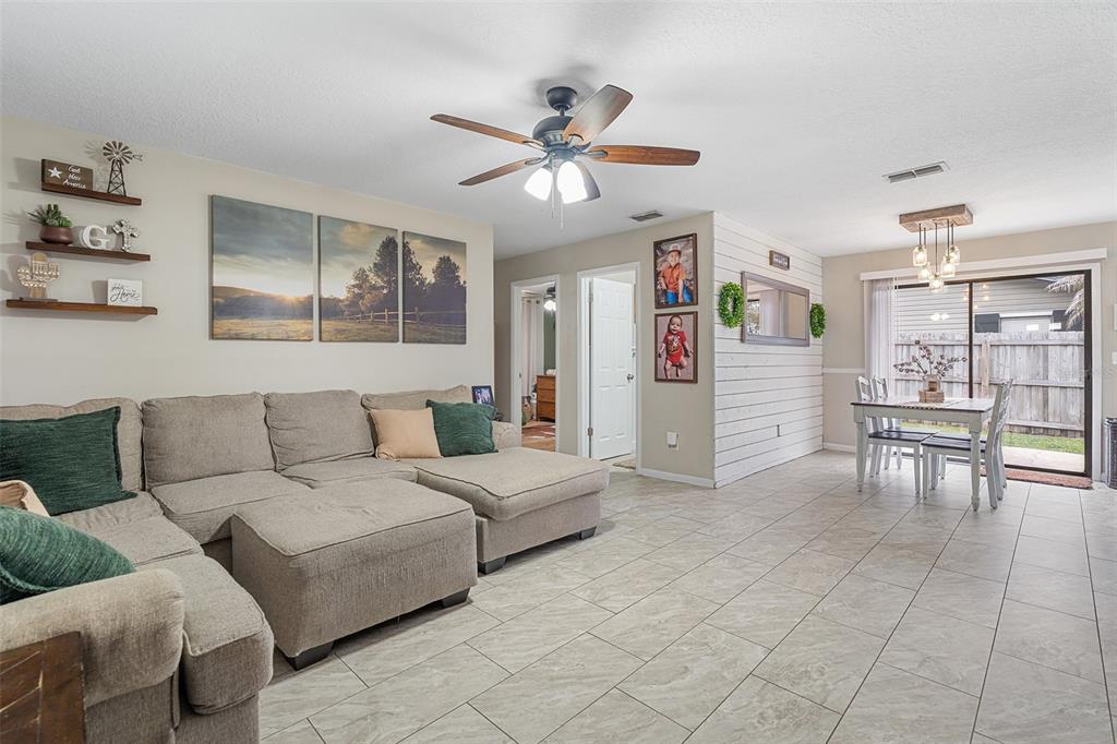 A living room with a sectional sofa, tiled floors, and an adjacent dining area — 1600 MINNESOTA AVE, ST CLOUD, FL
