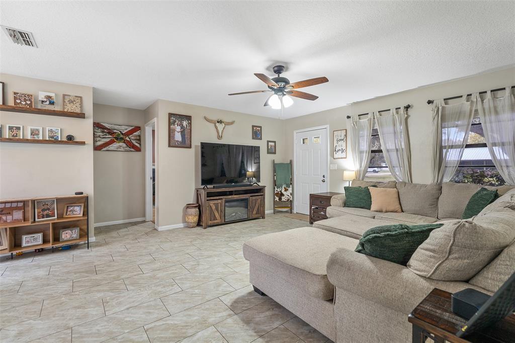 A living room features tile flooring, a sectional sofa, a television, and a ceiling fan — 1600 MINNESOTA AVE, ST CLOUD, FL