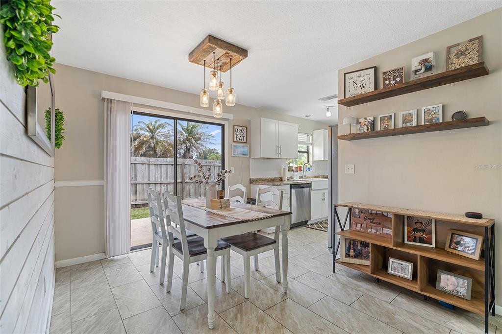 A dining area with a wooden table, farmhouse-style lighting, and open shelving against a beige wall — 1600 MINNESOTA AVE, ST CLOUD, FL