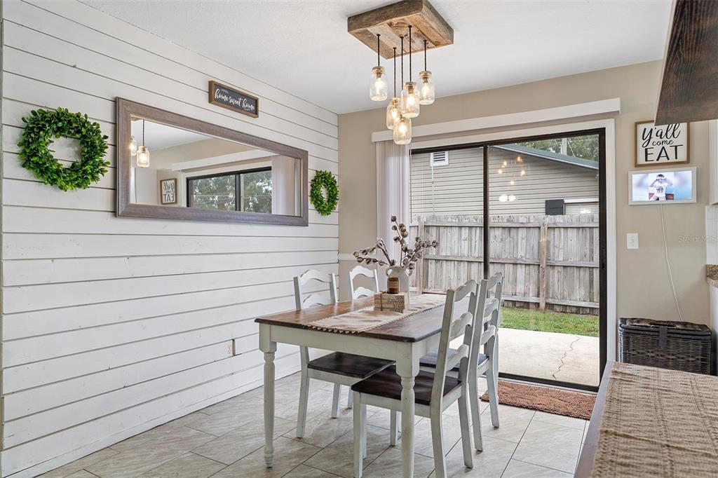 A dining room features a shiplap wall, a wooden chandelier, and a sliding glass door — 1600 MINNESOTA AVE, ST CLOUD, FL