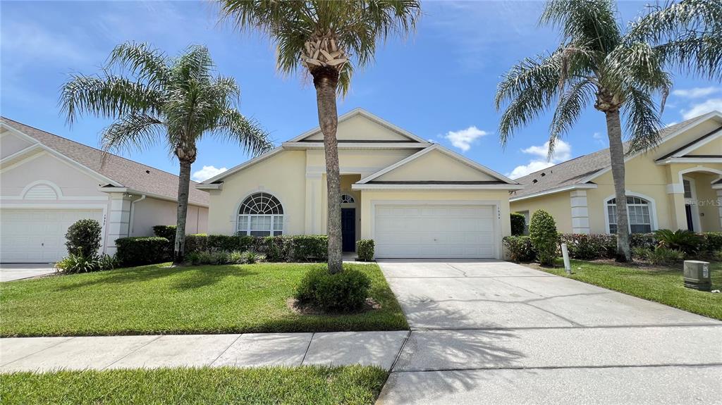 A single-story yellow house with a two-car garage and palm trees in the front yard — 1934 MORNING STAR DRIVE, CLERMONT, FL