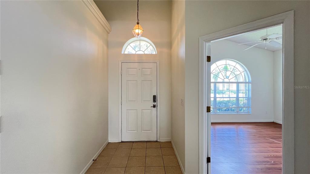 A tiled foyer with a pendant light leads to a doorway revealing a wood-floored room — 1934 MORNING STAR DRIVE, CLERMONT, FL