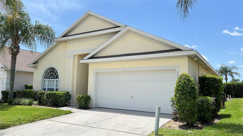 A single-story house with a yellow exterior, a two-car garage, and a palm tree — 1934 MORNING STAR DRIVE, CLERMONT, FL